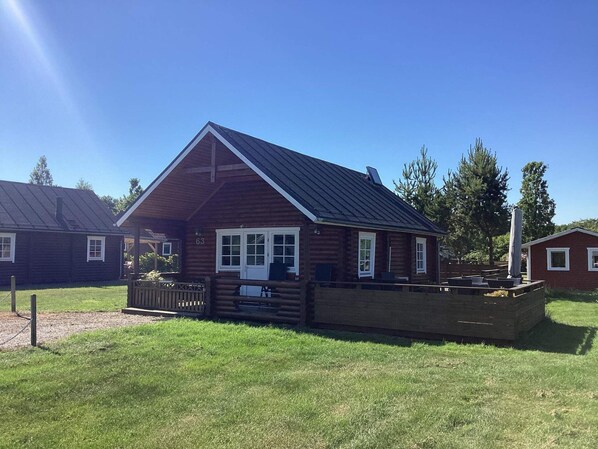A log cabin with a pitched roof, a deck, and a fenced yard. - 6 Person Holiday Home in Hovborg (Hovborg)