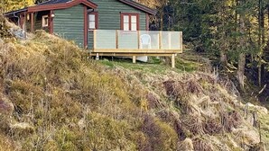 Ein grünes Haus mit einer Holzdiele und einem Stuhl.