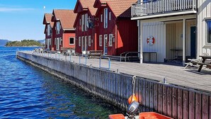 Un hôtel situé au bord de l’eau, avec des bâtiments aux couleurs rouge et blanc, un quai et une bouée de sauvetage.