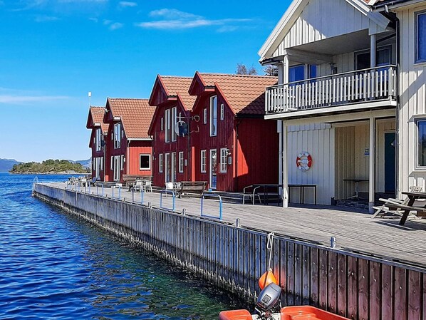 A waterfront hotel with red and white buildings, a dock, and a lifebuoy. - 7 Person Holiday Home in Sjernaroy (Stavanger)