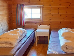 A cabin with two single beds, a small table, and a window with curtains. - 7 Person Holiday Home in Sjernaroy (Stavanger)