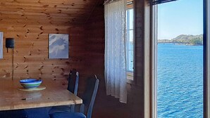 Une cabane en bois avec une table à manger, des chaises et une vue sur un plan d’eau.