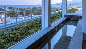 Ein modernes Gebäude mit einem Glasbalkon mit Blick auf eine Stadtlandschaft und das Meer.