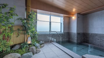 A modern indoor pool area with a glass barrier, bamboo plants, and a view through a large window.