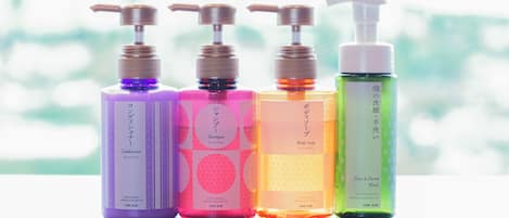 Four bottles of body care products with pumps, each in different colors and labeled in Japanese.