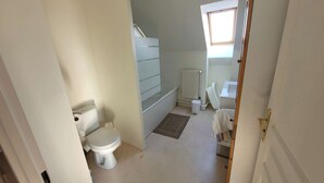 A small, clean bathroom with a toilet, a sink, and a window.