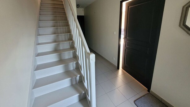 A staircase with white railings leading to a dark door at the bottom.