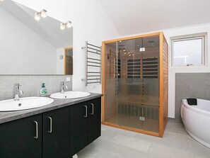 Bathroom features two sinks, a large mirror, and a glass-enclosed shower with a bathtub.