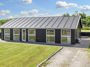 A modern building with a flat roof, large windows, and a gravel driveway. - 5 Star Holiday Home in Lokken (Lokken)