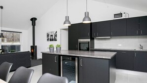 A modern kitchen with dark cabinetry, a central island, and pendant lighting.