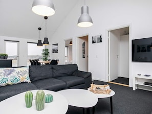 A modern living room with a grey sofa, a white coffee table, and a television on a white stand. - 5 Star Holiday Home in Lokken (Lokken)