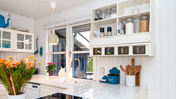 Una cocina moderna con armarios blancos, estufa integrada y un amplio ventanal.