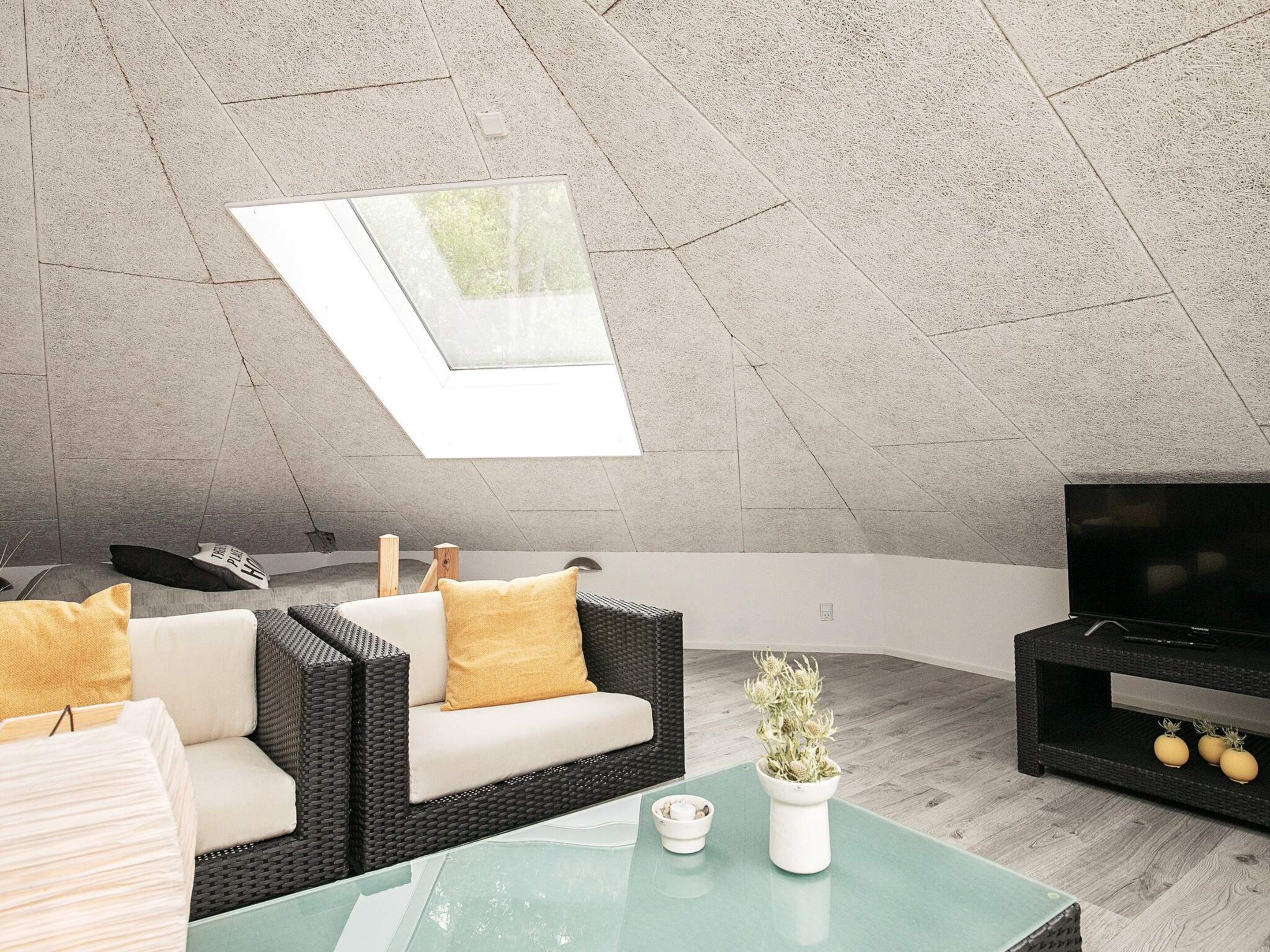 A modern living room with a high ceiling, a glass skylight, a sofa set, a flat-screen TV, and a coffee table.