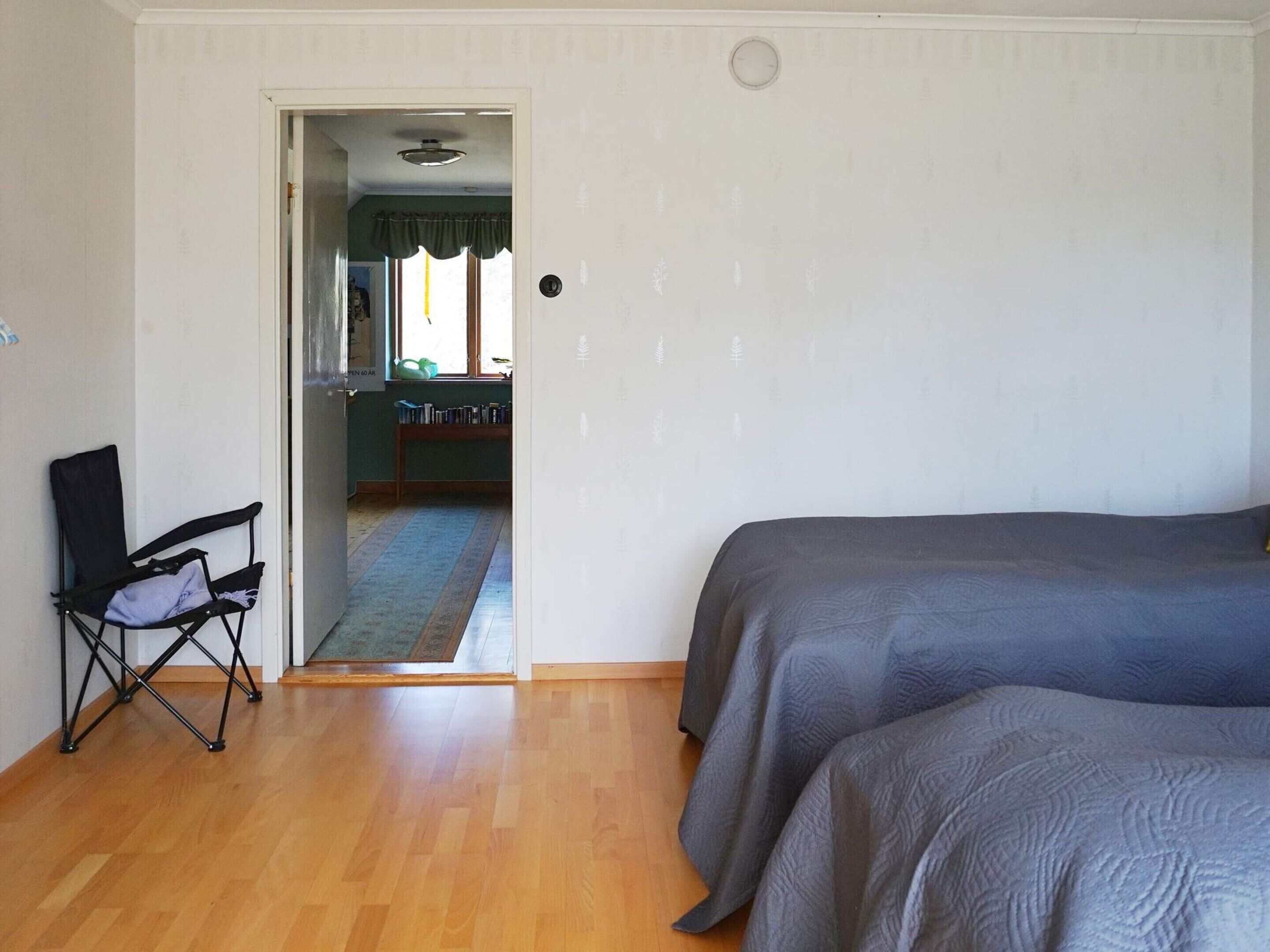 A room with two beds, a chair, a door leading to a bathroom, and a window with a view.