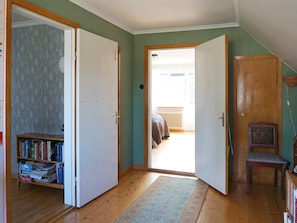 A room with a wooden floor, a bookshelf, a door leading to a balcony, and a chair. - 5 Person Holiday Home in Stanga (Stånga)