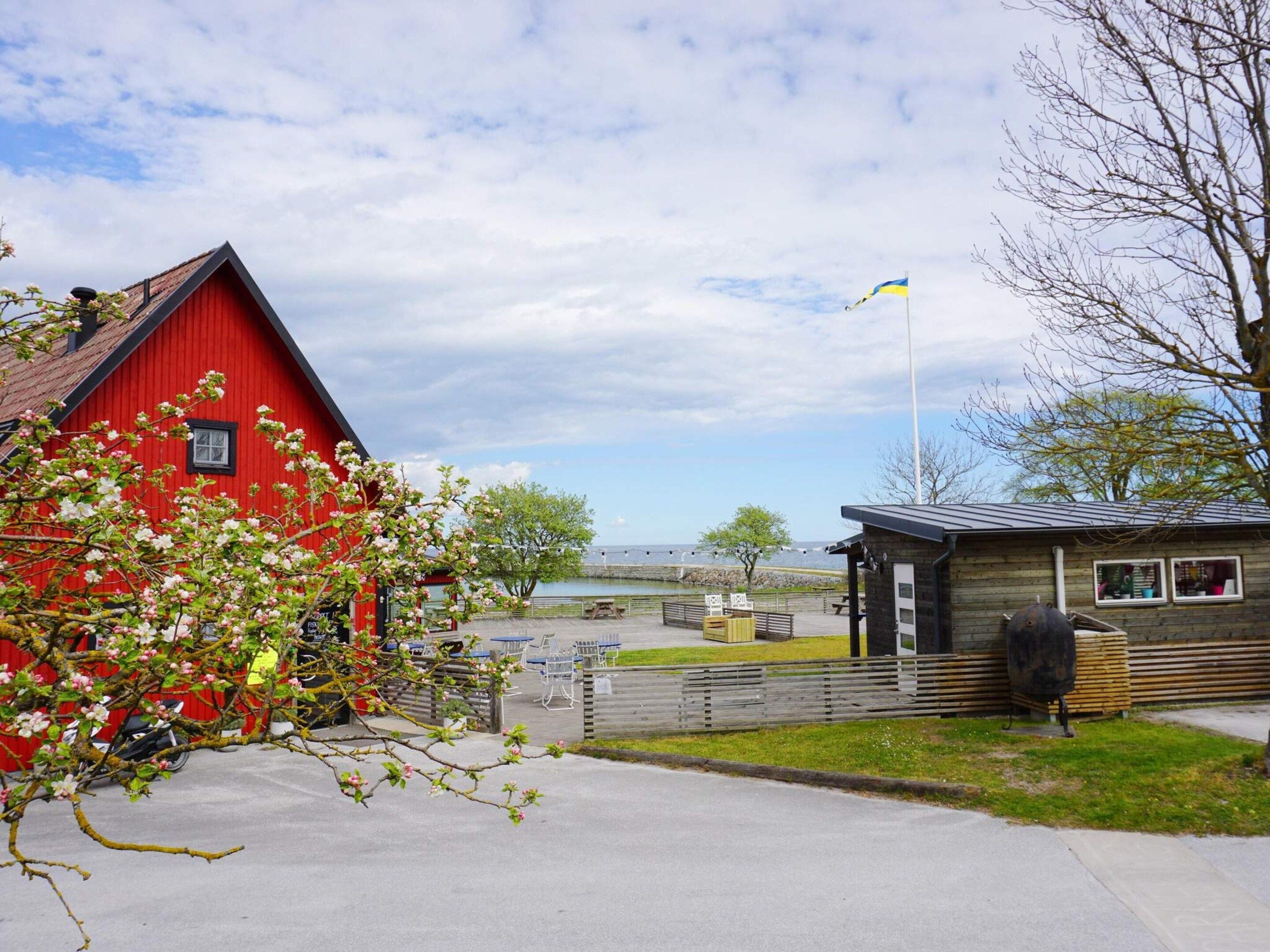 A red building with a flag, a wooden structure, and a view of a body of water.