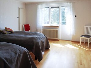 A room with two beds, a radiator, a chair, and a window with curtains. - 5 Person Holiday Home in Stanga (Stånga)