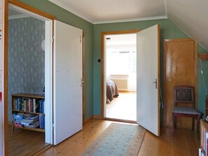 A room with a wooden floor, a bookshelf, a door leading to another room, and a chair. - 5 Person Holiday Home in Stanga (Stånga)