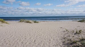 A sandy beach with gentle waves and a clear sky. - 5 Person Holiday Home in Stanga (Stånga)