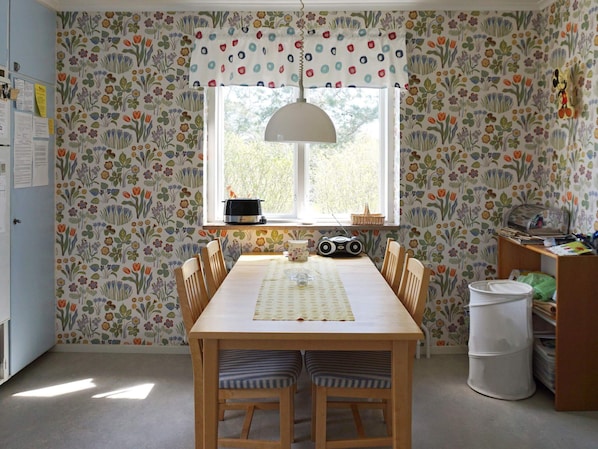 A dining area with a table, chairs, a window, and a radiator. - 5 Person Holiday Home in Stanga (Stånga)
