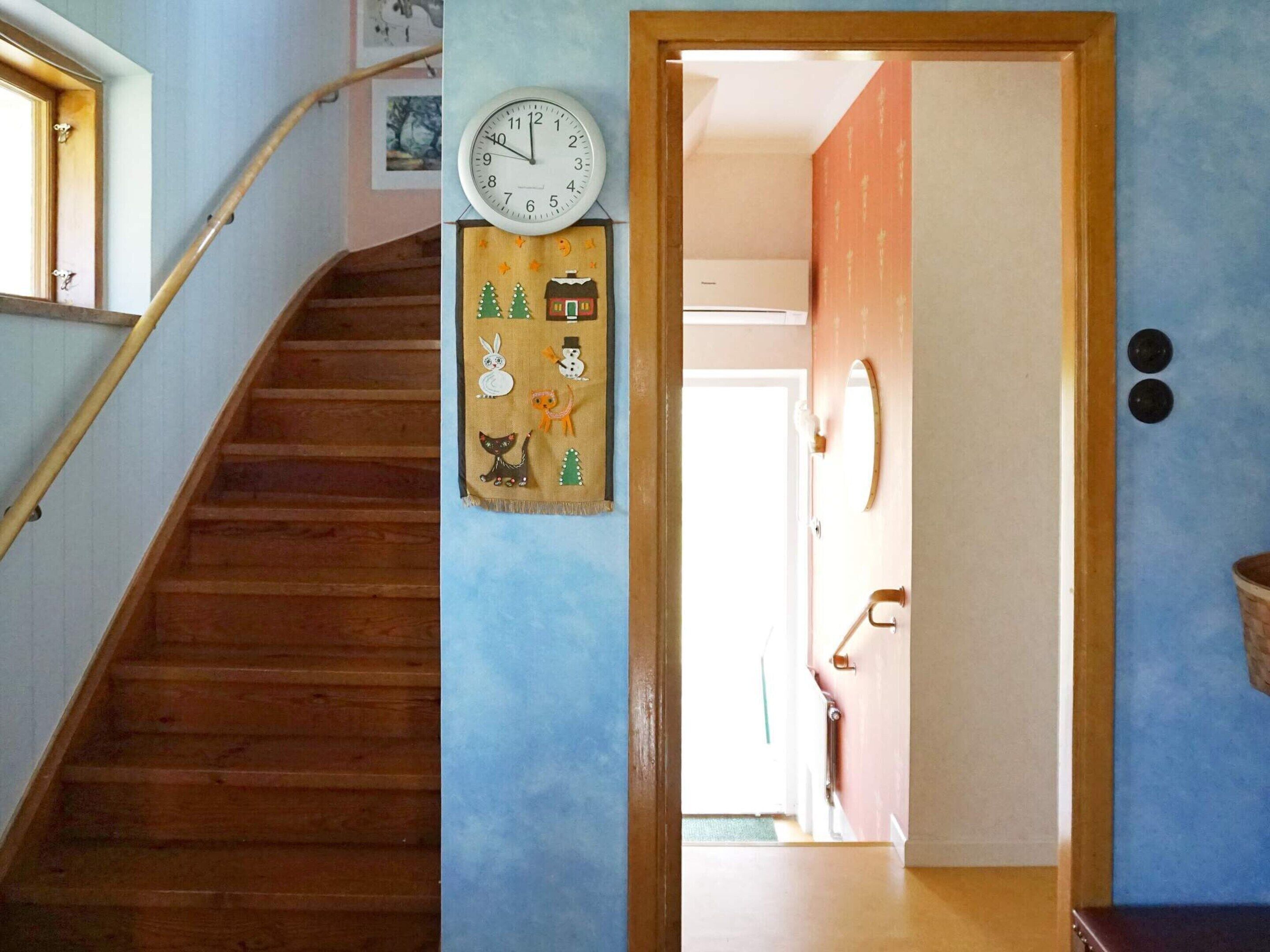A wooden staircase with a clock and a decorative panel with various figures.