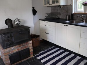 A kitchen with a brick stove, white cabinets, a black countertop, and a striped rug. - 4 Star Holiday Home in Munka-ljungby (Munka-Ljungby)