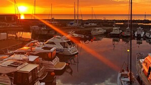 Un puerto deportivo con barcos fondeados al atardecer.
