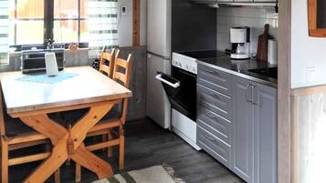 A compact kitchen with a dining table, chairs, a stove, oven, and cabinets.