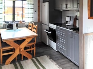 A compact kitchen with a dining table, chairs, a stove, oven, and cabinets.