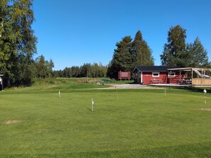 A golf course with a red building, a picnic area, and a clear sky.