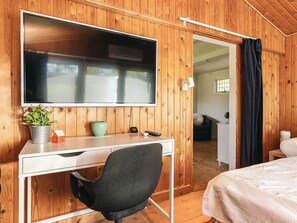 A room with a wooden interior, a bed, a desk with a chair, a television, and a small potted plant. - 4 Person Holiday Home in Faxe Ladeplads (Faxe Ladeplads)