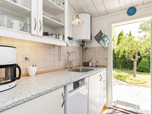 A kitchen with a coffee maker, a sink, and a dishwasher. - 4 Person Holiday Home in Faxe Ladeplads (Faxe Ladeplads)
