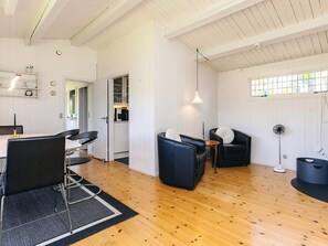 A spacious room with a wooden floor, a dining area with a table and chairs, a seating area with sofas, and a kitchen visible through an open door. - 4 Person Holiday Home in Faxe Ladeplads (Faxe Ladeplads)