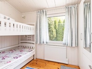 A room with bunk beds, a window with curtains, a radiator, and a wooden floor. - 4 Person Holiday Home in Faxe Ladeplads (Faxe Ladeplads)