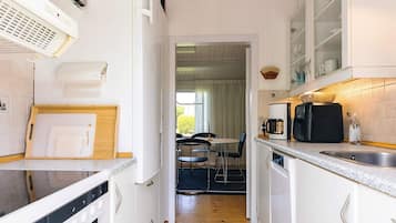 A compact kitchen with white cabinets, a microwave, a coffee maker, and a small sink.