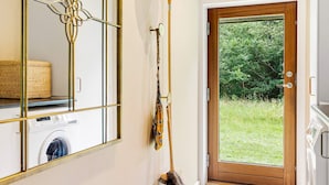 A laundry room with a washing machine, a door leading to a garden, and a mirror with a decorative frame. - 4 Star Holiday Home in Jerup (Jerup)