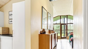 A narrow hallway with a wooden cabinet, framed artwork, and a large window leading to an outdoor area. - 4 Star Holiday Home in Jerup (Jerup)
