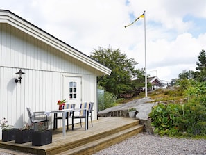 A white building with a deck, a flagpole, and a bench with a table.