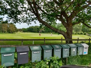 Un parcours de golf avec une clôture en bois et des poubelles vertes pour les déchets, chacune étant étiquetée avec un nom.