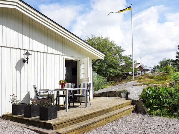 A white building with a wooden deck, outdoor seating, and a flag.