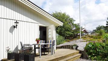 A white building with a wooden deck, outdoor seating, and a flag.