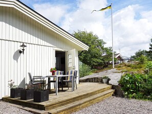 A white building with a wooden deck, outdoor seating, and a flag. - 2 Person Holiday Home in Stromstad (Stromstad)