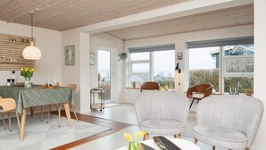 Een moderne eetruimte met een houten plafond, een tafel met een groene tafelkleed en twee grijze stoelen.