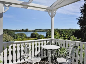 A covered outdoor area with a white railing, two metal chairs, and a small table. - 4 Star Holiday Home in Mellerud (Mellerud)