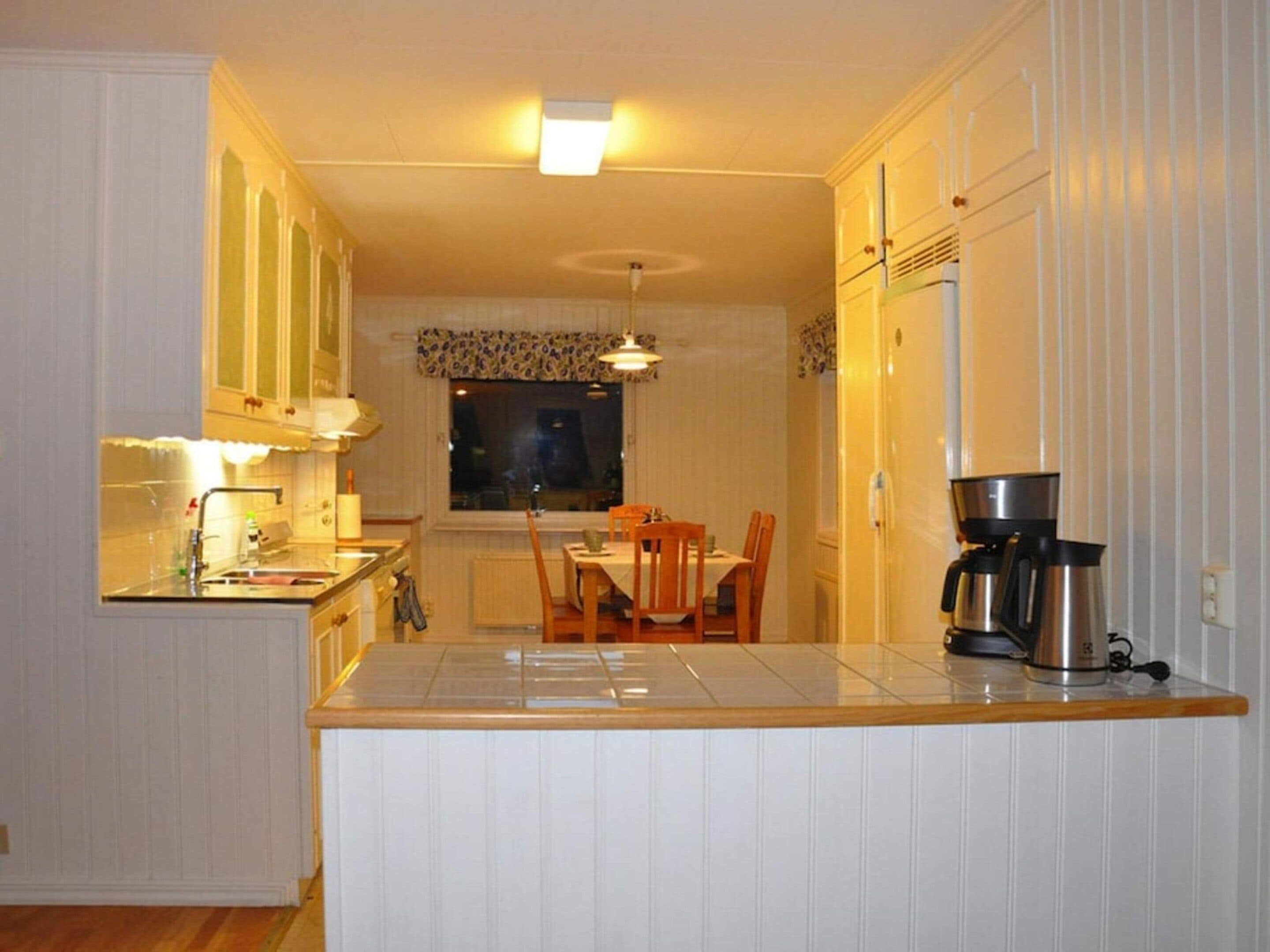 A compact kitchen with white cabinetry, a central island, and a dining area with a table and chairs.