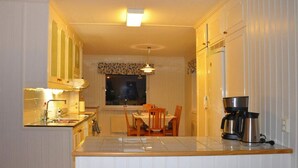 A compact kitchen with white cabinetry, a central island, and a dining area with a table and chairs. - 4 Star Holiday Home in Mellerud (Mellerud)