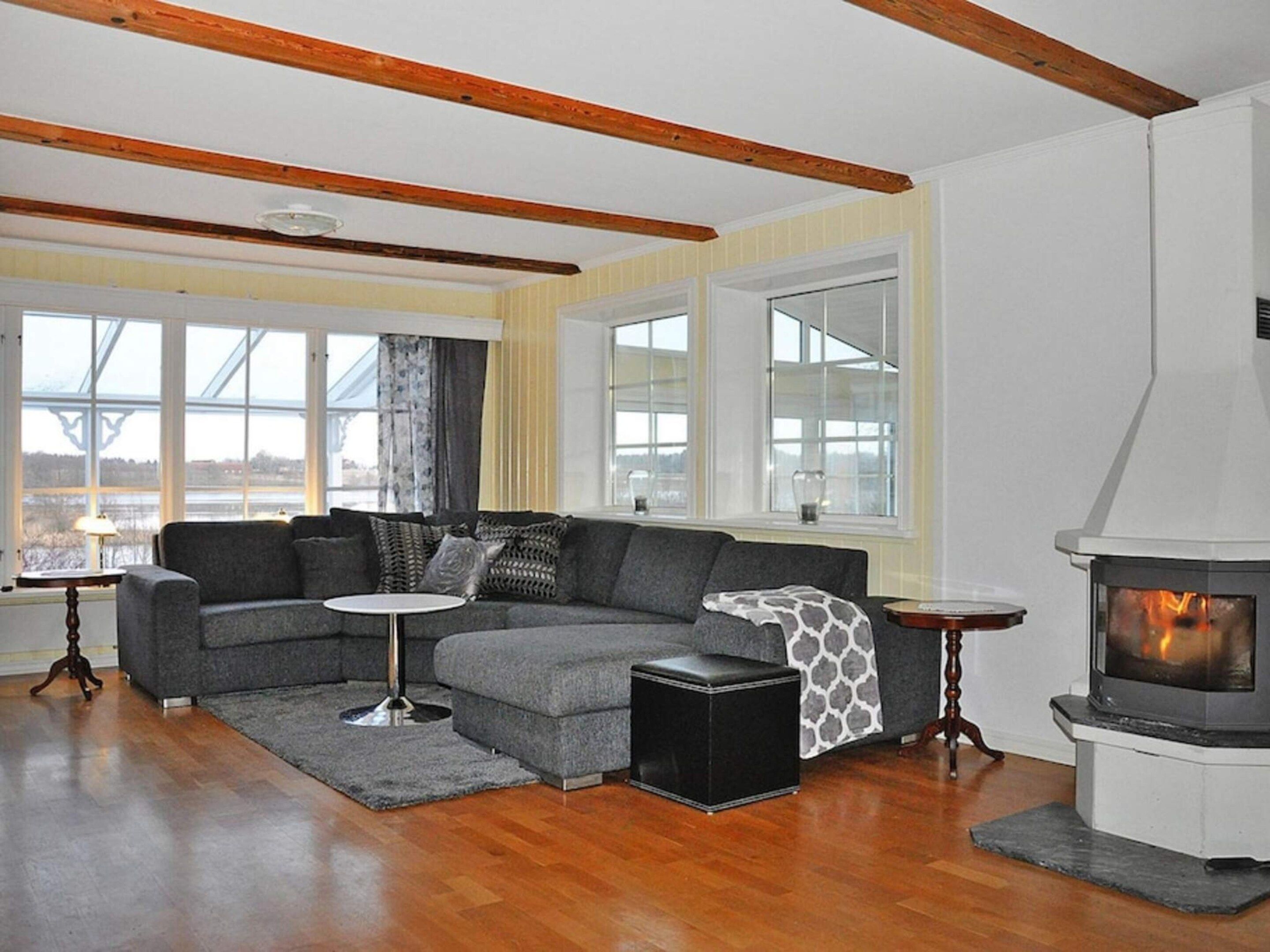 A modern living room with a sectional sofa, a fireplace, and large windows.