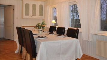 A dining room with a table set for four, chairs, a plant, and a window with curtains.