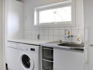 A laundry area with a washing machine, a sink, and a window above the sink. - 4 Star Holiday Home in Mellerud (Mellerud)