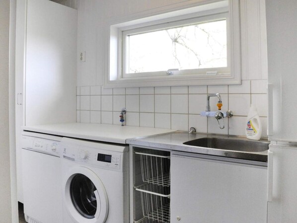 A laundry area with a washing machine, a sink, and a window above the sink.